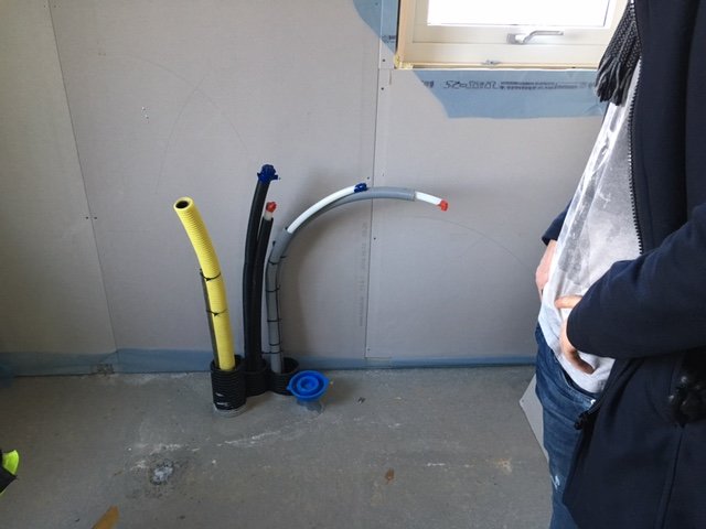 Avloppsrör som sticker upp i en ofärdig tvättstuga med osätt gipsskivor och en synlig innervägg.