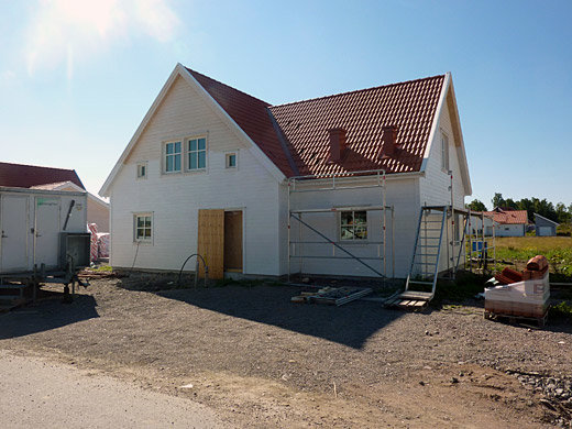 Vit villa under konstruktion med synligt garagetak och husets taknock.
