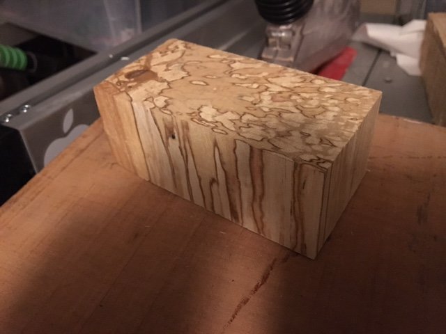 Ett kort block av björkplywood med synligt ådringsmönster ligger på ett bord, möjligen för träslagsidentifiering eller ett projekt.