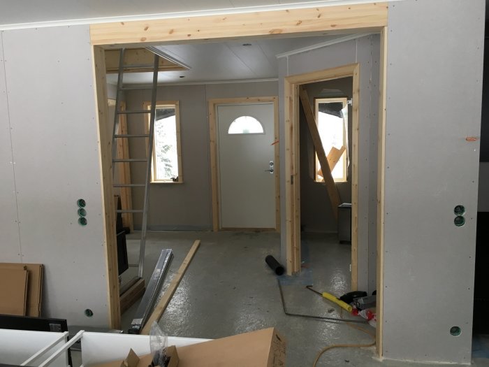 Omonterade dörrkarmar i ett rum under renovering med synlig betonggolv och oavslutade väggar.