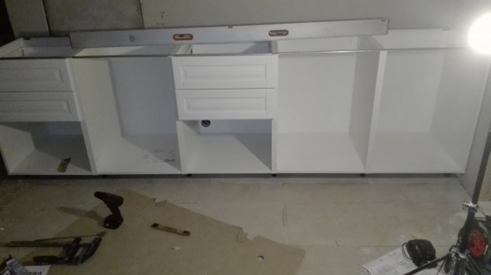 Nyinstallerade vita kökslådor med mjukstängande funktion och verktyg på golvet.