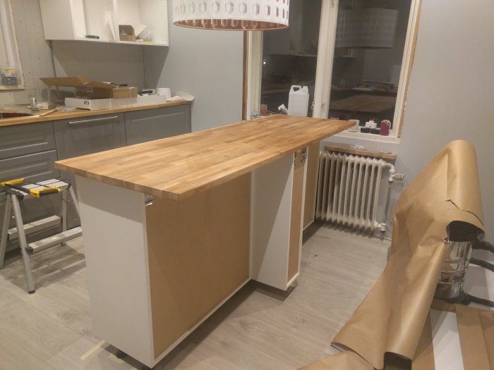 Halvfärdig köksö i ett kök under renovering med verktyg och byggmaterial synliga.