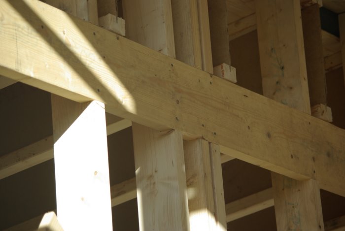 Träavväxling installerad för att fördela vertikala krafter i en träregelvägg under konstruktion.