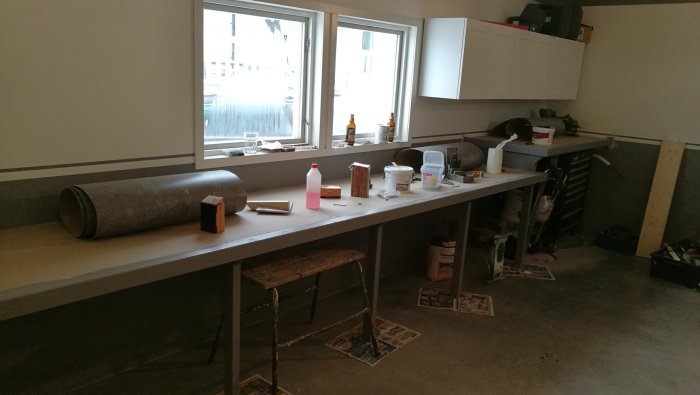 Renoverat garage med monterade bänkar och linoleummattor, målningsmateriel synlig.