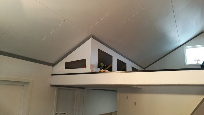 Loftsförvaring med monterade golvlister och ny målad ram under snedtak.