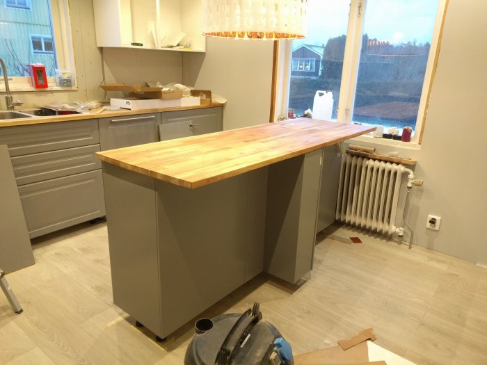 Köksö under renovering med omonterade handtag och en träskiva som behöver slipas och oljas.