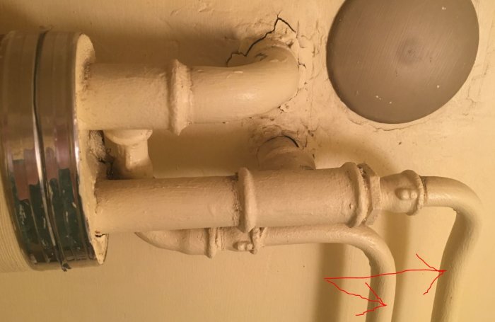 Stålrör från en radiator målade i beige med en indikation om var ballofix bör monteras eller var rören ska pluggas, markerat med röda pilar.