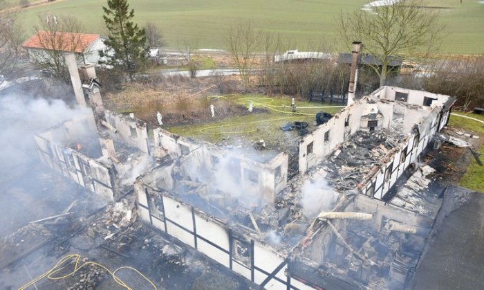 Överblick av ett nedbrunnet hus med stående väggar och rasmassor, lämplig för diskussion om renovering efter brand.