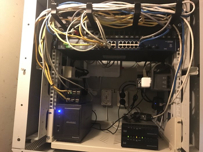 Nätverksskåp med en ny 24-portars Netgear-switch, kablar och annan nätverksutrustning.