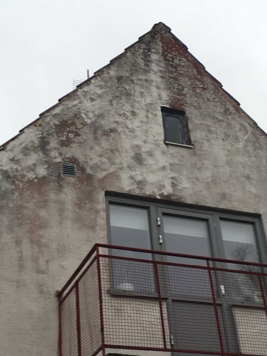 Vitmålad tegelhusfasad med röda blödningar liknande rinnande färg.