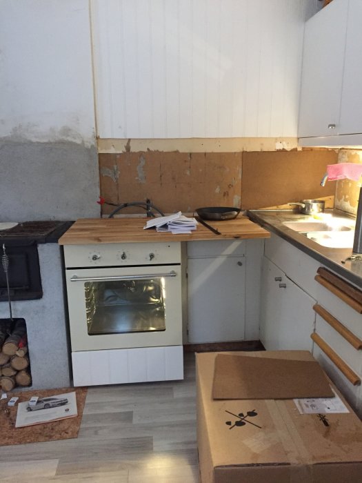Kök under renovering med omonterade skåpsdelar och en temporär bänkskiva.