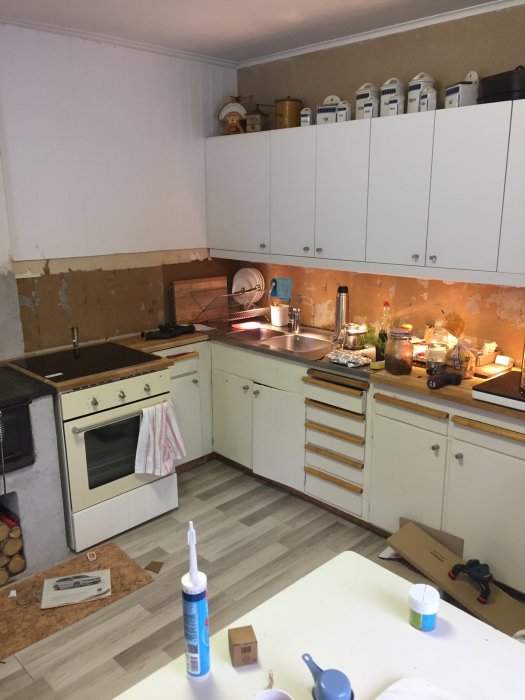Kök under renovering med installerad och provkörd ugn och spishäll, ofullständiga bänkskivor och renoveringsmaterial.