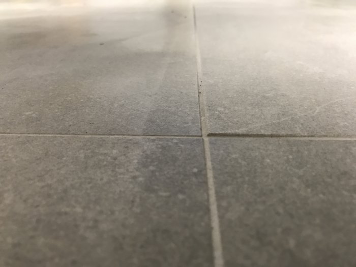 Närbild på felaktigt liggande granitkeramikplattor med märkbar nivåskillnad vid fogarna.