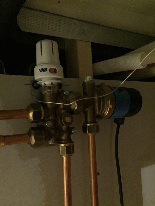 VVS-installation med kopparledningar och ventiler i ett mörkt utrymme.