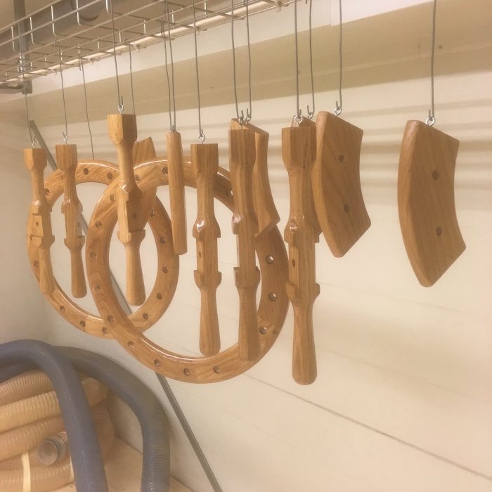 Trähantverk med rundade delar och borrade hål, upphängda för torkning eller montering.