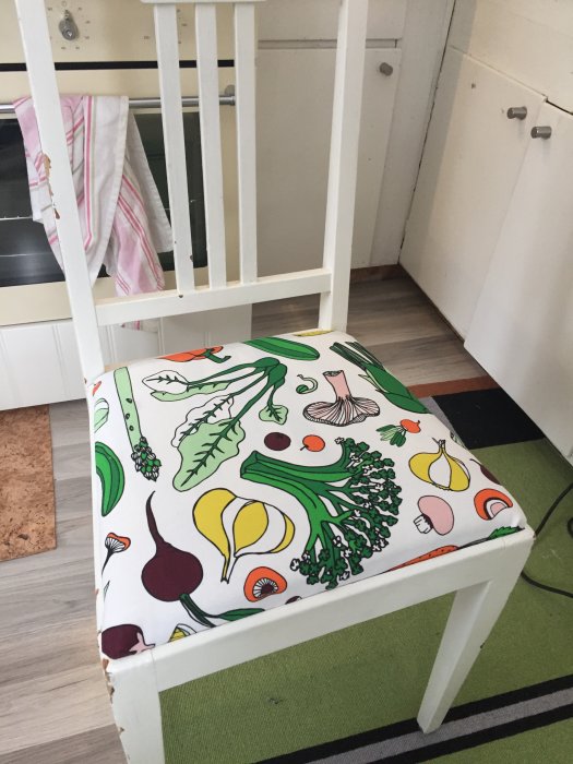 Vit köksstol med nytt färgglatt tyg med grönsaksmotiv omdesignat av en elvaåring.