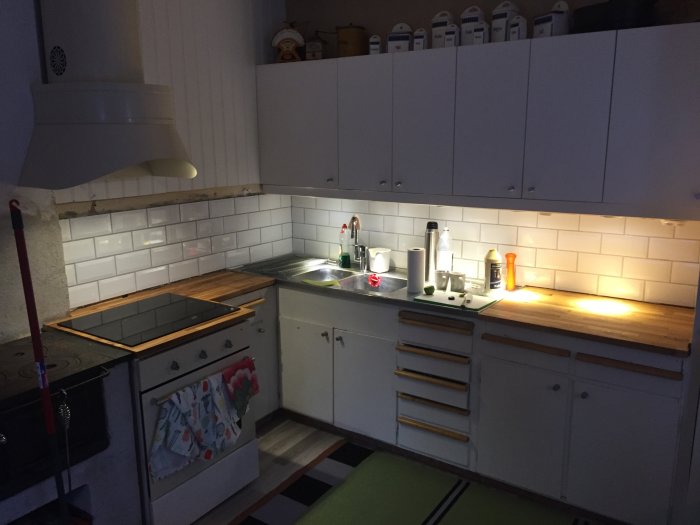 Nyrenoverat kök med vita skåp, träbänkskivor, spishäll, kakelvägg och inbyggd ugn.