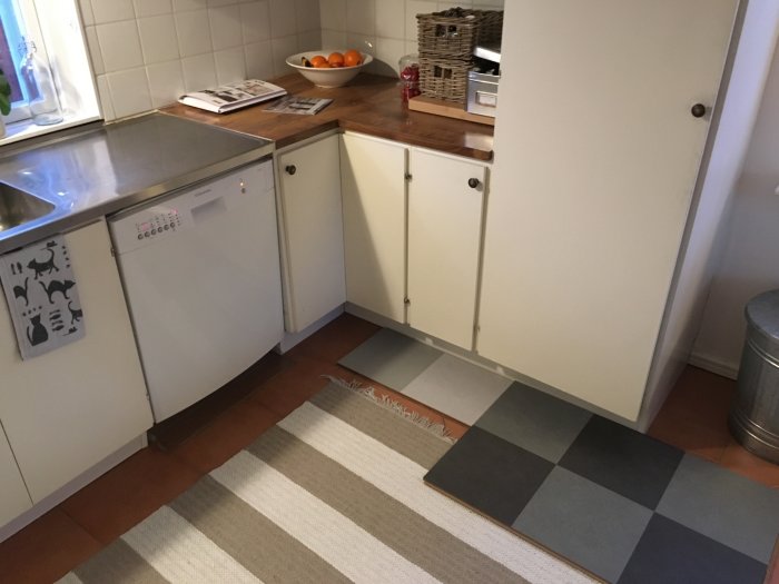 Kök med befintligt golv och mörka samt ljusa Marmoleum Click 30x30cm plattor i ett rutigt mönster.