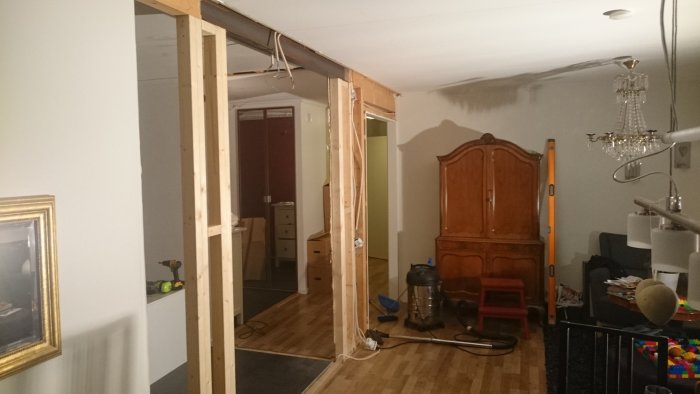 Renoveringsprojekt med trästommar, exponerad el och oavslutade väggar i ett vardagsrum.