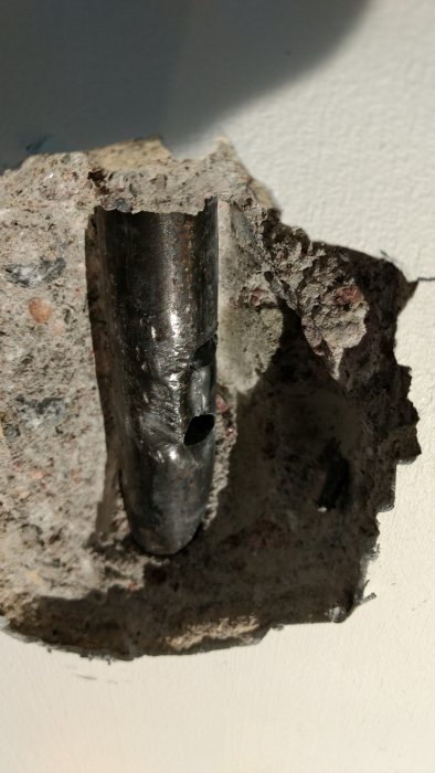 Skadat stålrör i vägg med borrschakt och två hål efter felaktig borrning under köksrenovering.