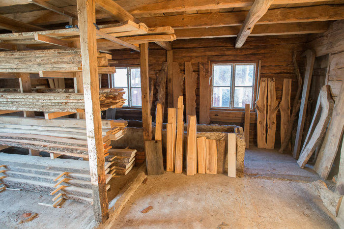 Inredning av träbutik med olika träslag staplade på hyllor och liggandes mot väggar.