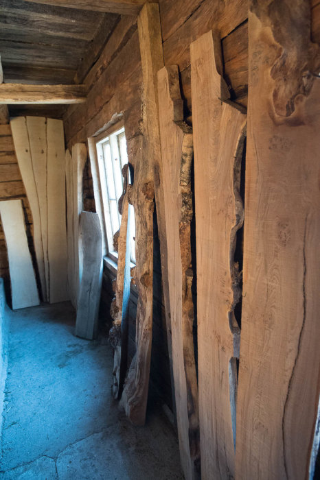 Sågade träplankor av olika träslag staplade i en rustik träinredning.