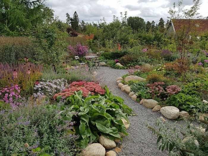 Välansad biträdgård med grusgång omgiven av blommande växter och stenkanter, redo för pollinering.