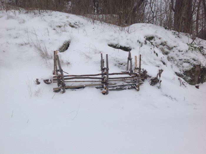 En hemmagjord kompost av grenar och skidor i ett snötäckt landskap.