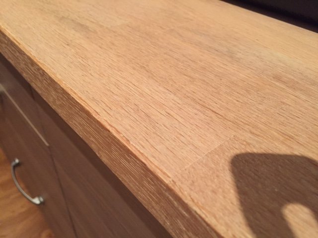 Obehandlad ek köksbänkskiva som visar slitage och behov av renovering.