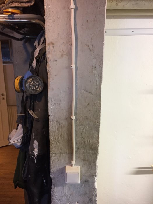 Nyinstallerad strömbrytare med plaströr för kablar på en betongvägg i ett renoveringsprojekt.