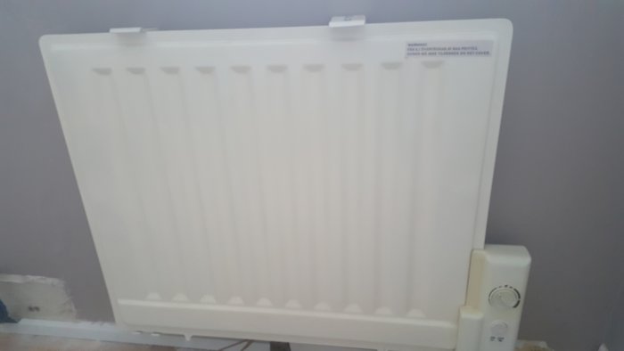 Elektriskt element 500w 400v monterat på vägg, komplett med väggfäste och termostat, i ett rum.