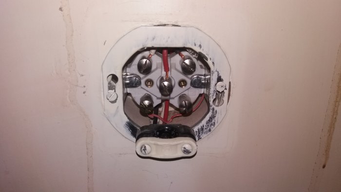 Öppet elektriskt uttag med vit, svart och röd tråd, redo för installation av vägguttag.