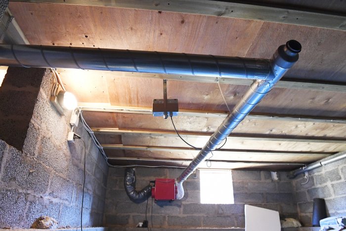 Installation av ventilation i källartak med synliga rör och isolering mot träbjälklag.