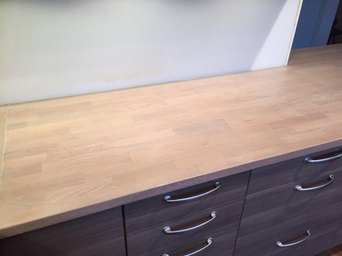 Renoverad bänkskiva med ljust träfinish behandlad med Osmo Top-oil, belägen ovanpå grå skåp med silverhandtag.