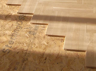 Trägolv med not och spont i skarven ovanpå OSB-skivor.