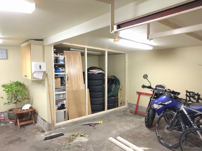 Ett garage under renovering med nyreglade väggar, isolering, motorcykel och cyklar.