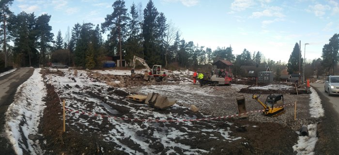 Panoramabild av en byggarbetsplats med grävmaskiner, röjda markområden och snö.