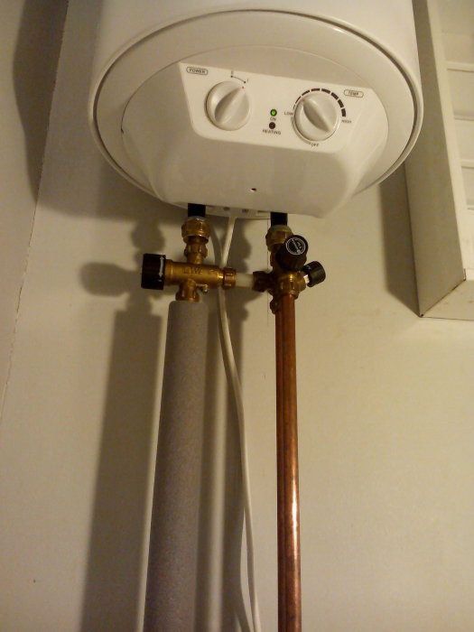 Nyinstallerad Biltema varmvattenberedare med justerbara ventiler och kopparledningar.