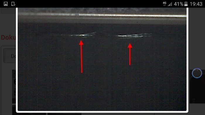 Bild på föremålets yta med två markerade skador och röda pilar som pekar på dem.