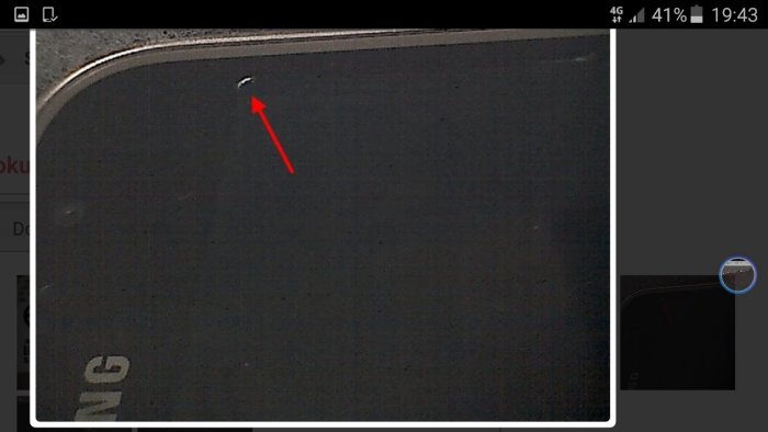 Mörk skärmdisplay med en synlig skada uppmärkt med en röd pil i övre vänstra hörnet.