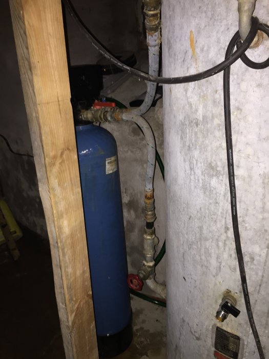 En hydrofor med anslutna rör och ventiler i ett källarutrymme, troligtvis en del av en vattentillförselsystem.