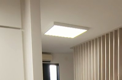 Kvadratisk takplafond med LED-lampor monterad i ett vitt rum med vertikala persienner.