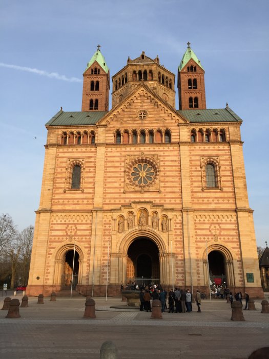 Katedralen i Speyer mot en klarblå himmel, med besökare vid ingången.