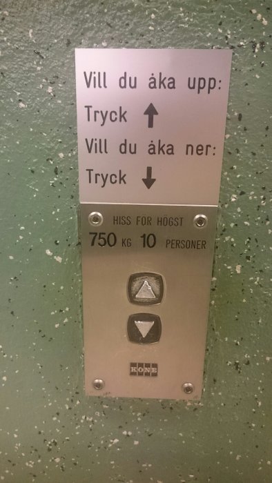 Hissknappar med instruktionsskylt som förklarar vilken knapp man ska trycka för att åka upp eller ner.