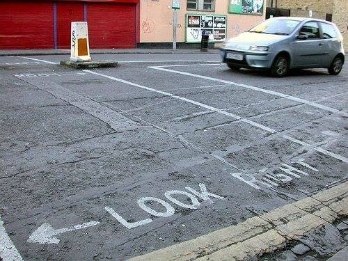 Parkering med vägmarkering "Look Right" och en bil som närmar sig från vänster.