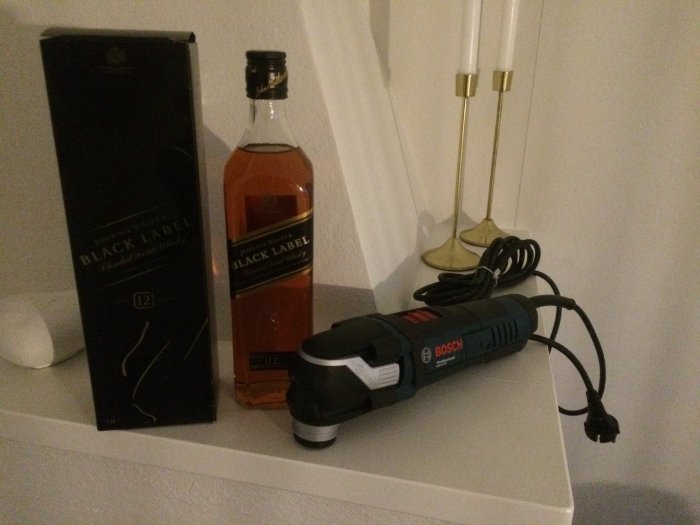 Bosch GOP 40-30 multisåg på ett bord bredvid en flaska och låda av Johnnie Walker Black Label och två vita bordslampor.