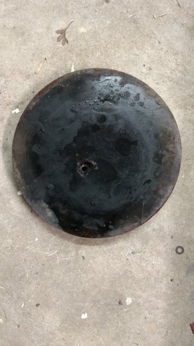 Rostig kokplatta med sönderrostat hål placerad på betonggolv.