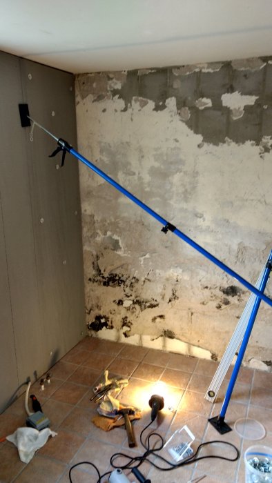 Pågående renovering av duschutrymme med synlig gjuten platta i golvet och verktyg.