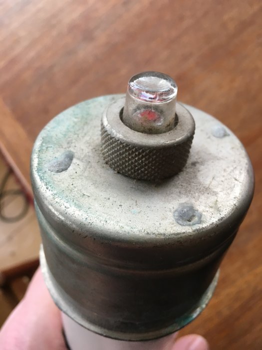 Stor rörsäkring med metalländar och glasplupp med röd markering, möjligtvis porslin.