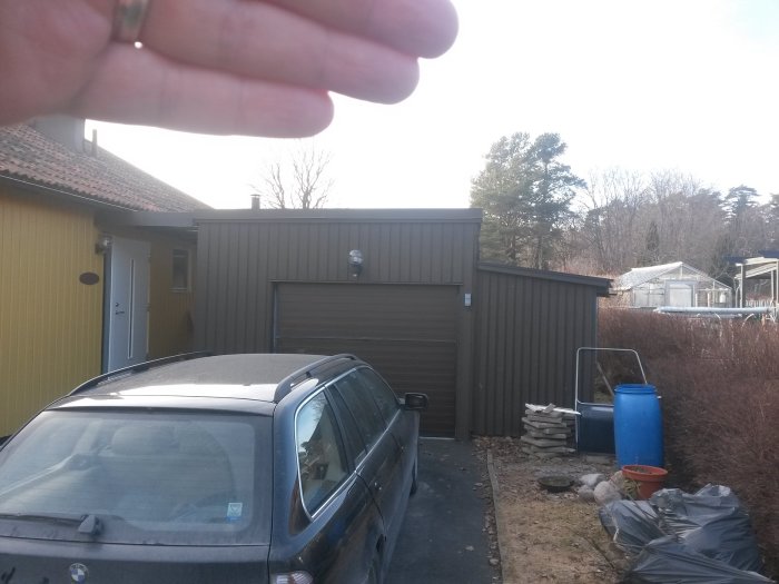 Utsikt över en villa och ett oisolerat garage med en potentiell tillbyggnad av en hall markerad av en hand.